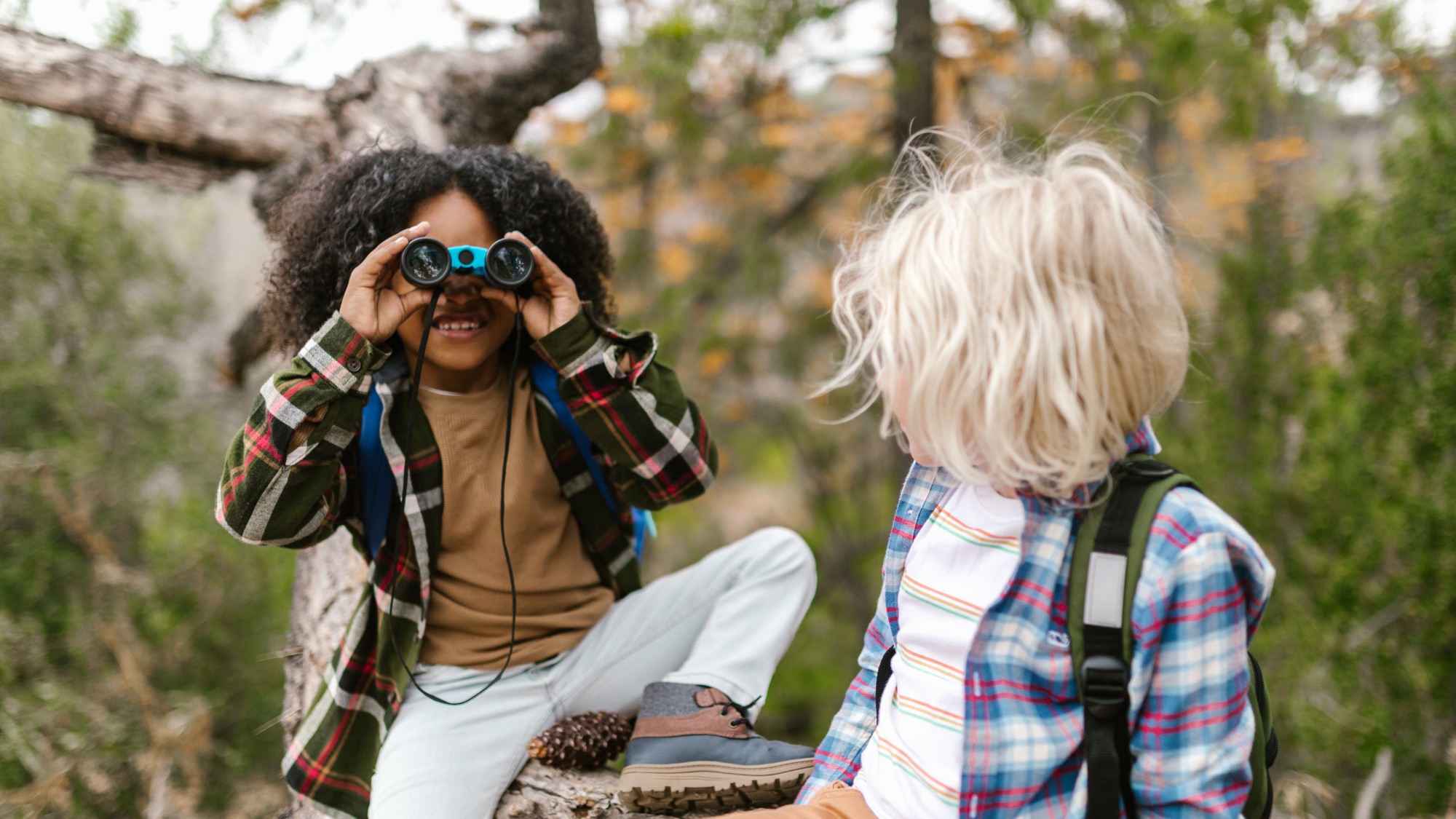 Two children playing outdoors with binoculars