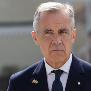 Prime Minister Mark Carney with a pensive serious look on his face wearing a blue suit from the shoulders up with a blurred background