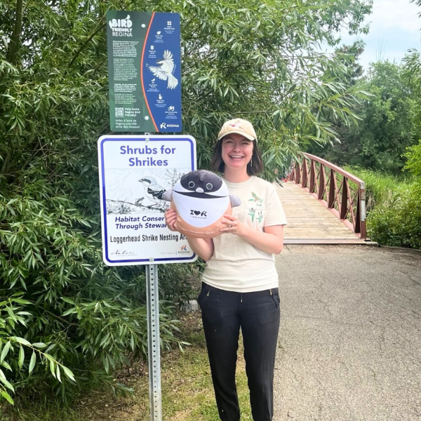 Angela Tremka of Bird Friendly Regina outside the Citie's Bird Friendly Regina Sign